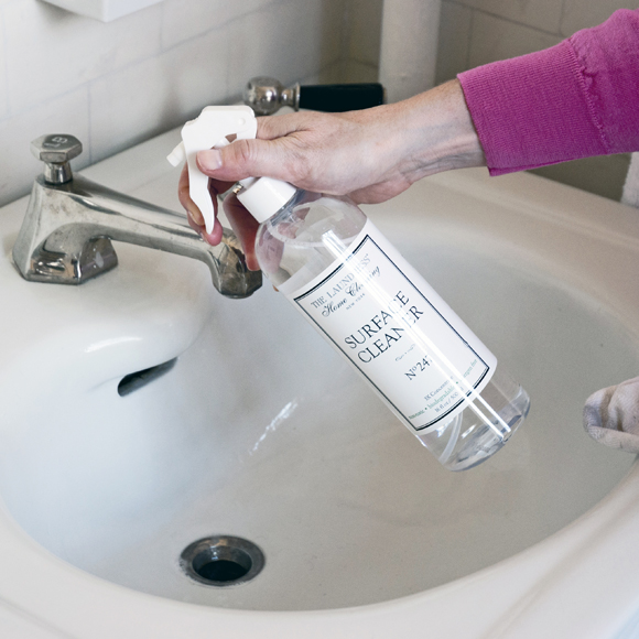 hand spraying surface cleaner on sink