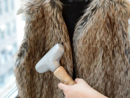 A faux fur jacket being steamed after being washed with The Laundress fabric care products. 