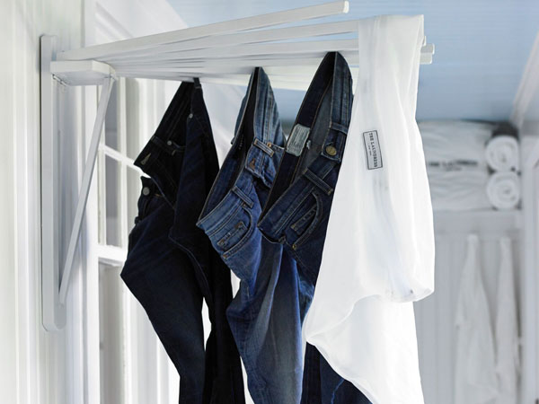 Four pairs of denim jeans dry on a clothesline after being washed with The Laundress fabric care products. 