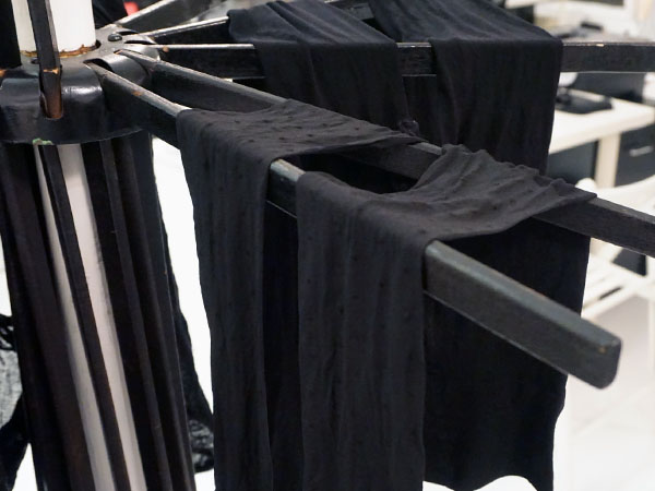 Tights hanging on a drying rack after being washed using The Laundress's method to clean & preserve black tights.