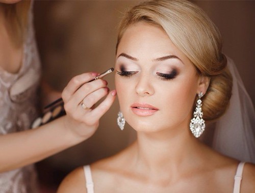 A bride gets her makeup professionally done on her wedding day.