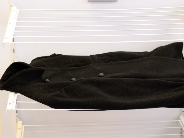 A wool coat is laid out on a drying rack after being washed with The Laundress's method for washing wool coats. 