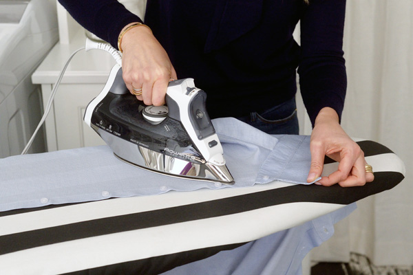 Woman using iron on ironing board